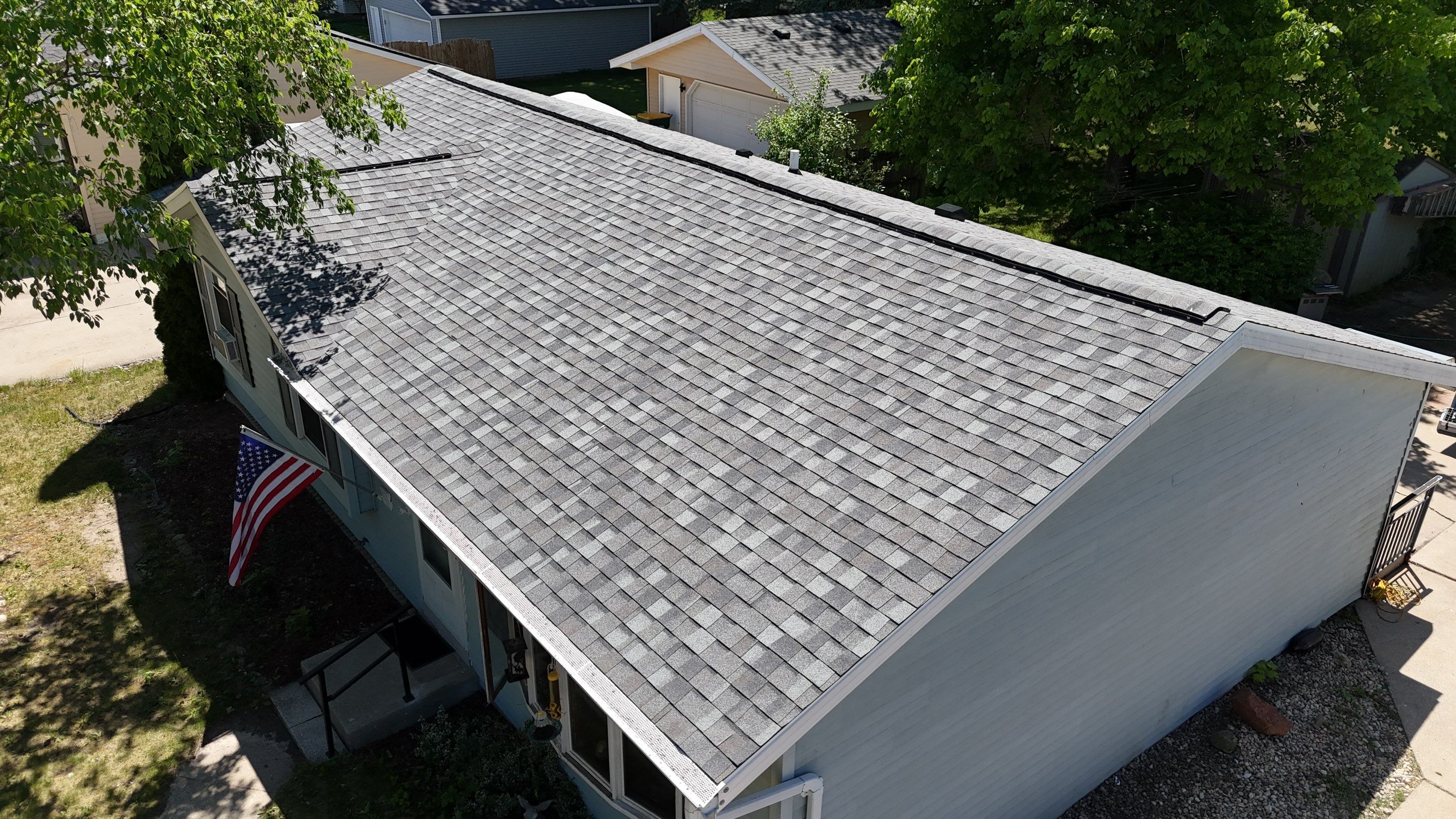 Angled aerial view of a maintained gray shingle roof on a single-story home